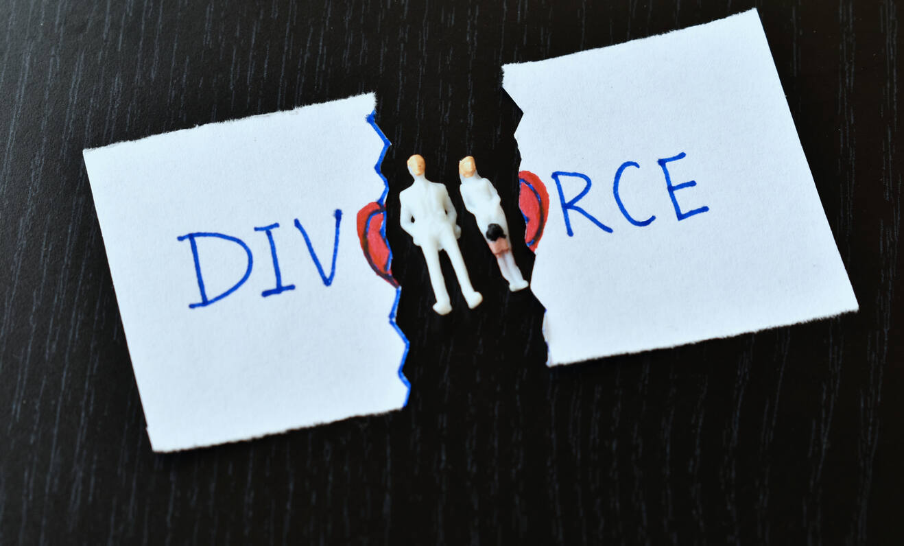 A man and a woman, possibly a client and their attorney, sit at a desk and review complex financial documents. The image represents the common and costly mistakes that can be made when dividing assets in a high-asset divorce and the need for expert legal counsel to avoid them