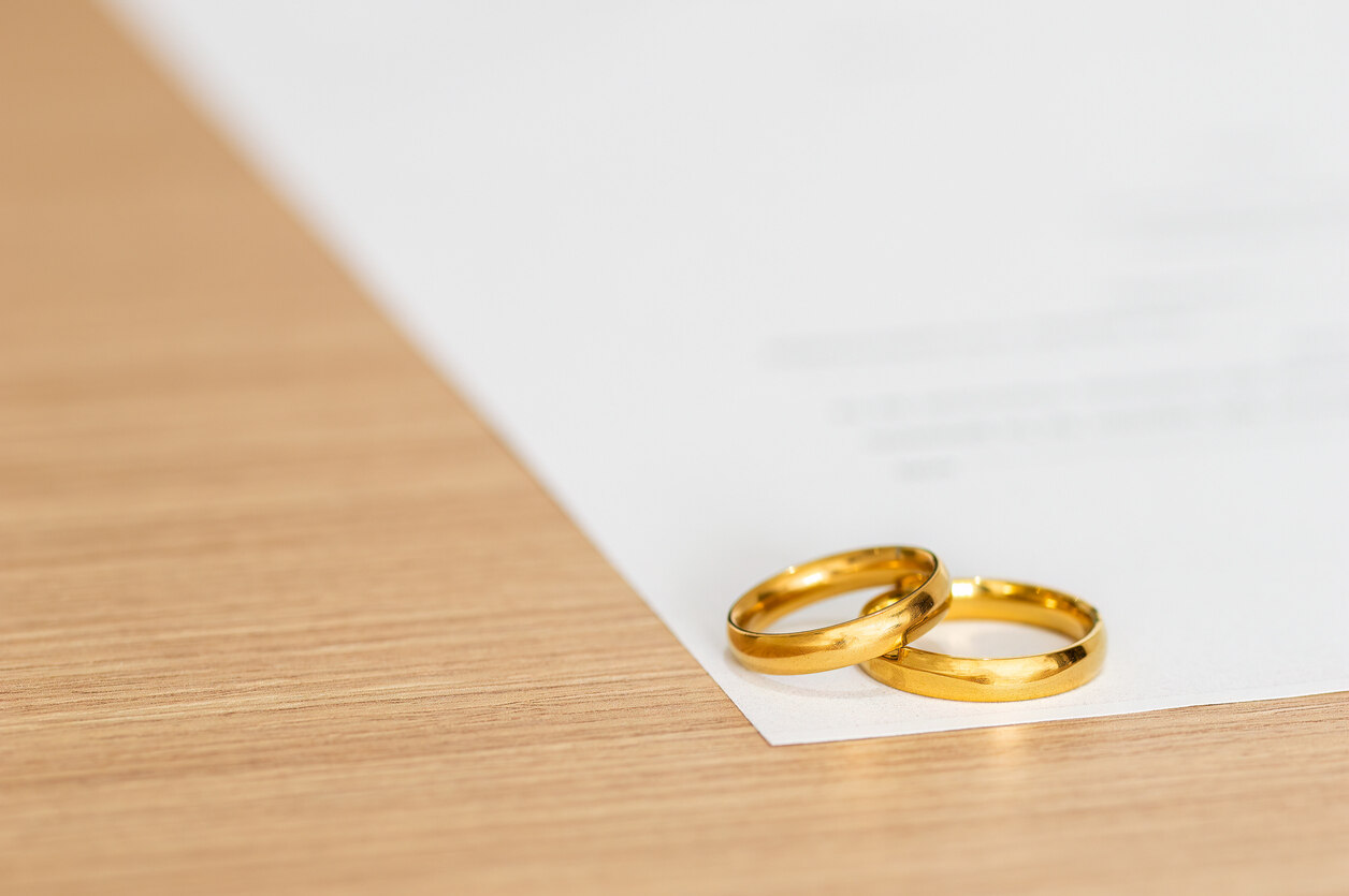 
Two gold wedding rings rest on a legal document, visually representing a prenuptial agreement. The image highlights the importance of the contract's enforcement in a California divorce.