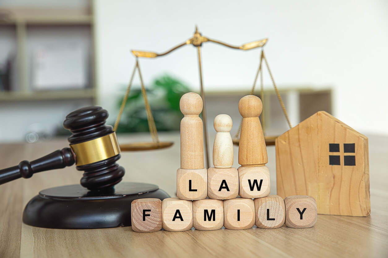 A gavel, family figurines, and blocks spelling "LAW FAMILY" symbolize the enforcement of family law orders across state or international borders.